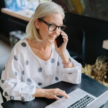 smiling woman talking on phone and looking at laptop